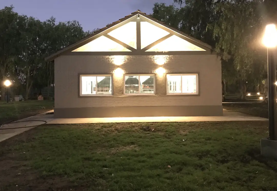 Un monoambiente de GyC iluminado al anochecer, con su galería y el parque adelante.