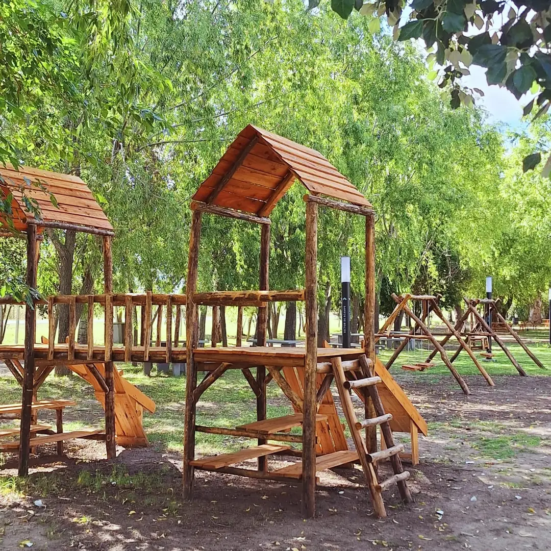 La plaza de juegos de madera bajo los árboles.