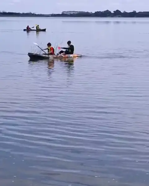 Dos kayaks con chicos remando en la laguna.