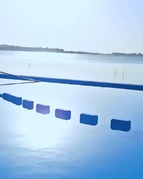 El borde de la pileta infinita y la laguna en calma, a la mañana.