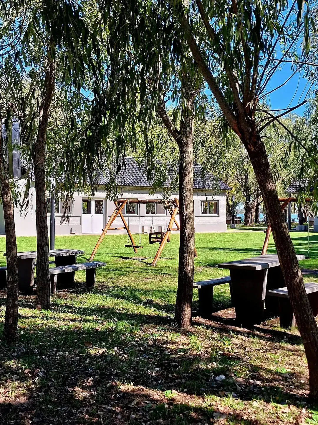 El parque del complejo, con pasto, árboles y bancos.