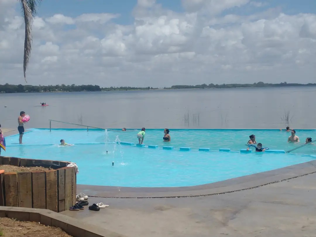 La pileta infinita frente a la laguna, con gente en el agua.