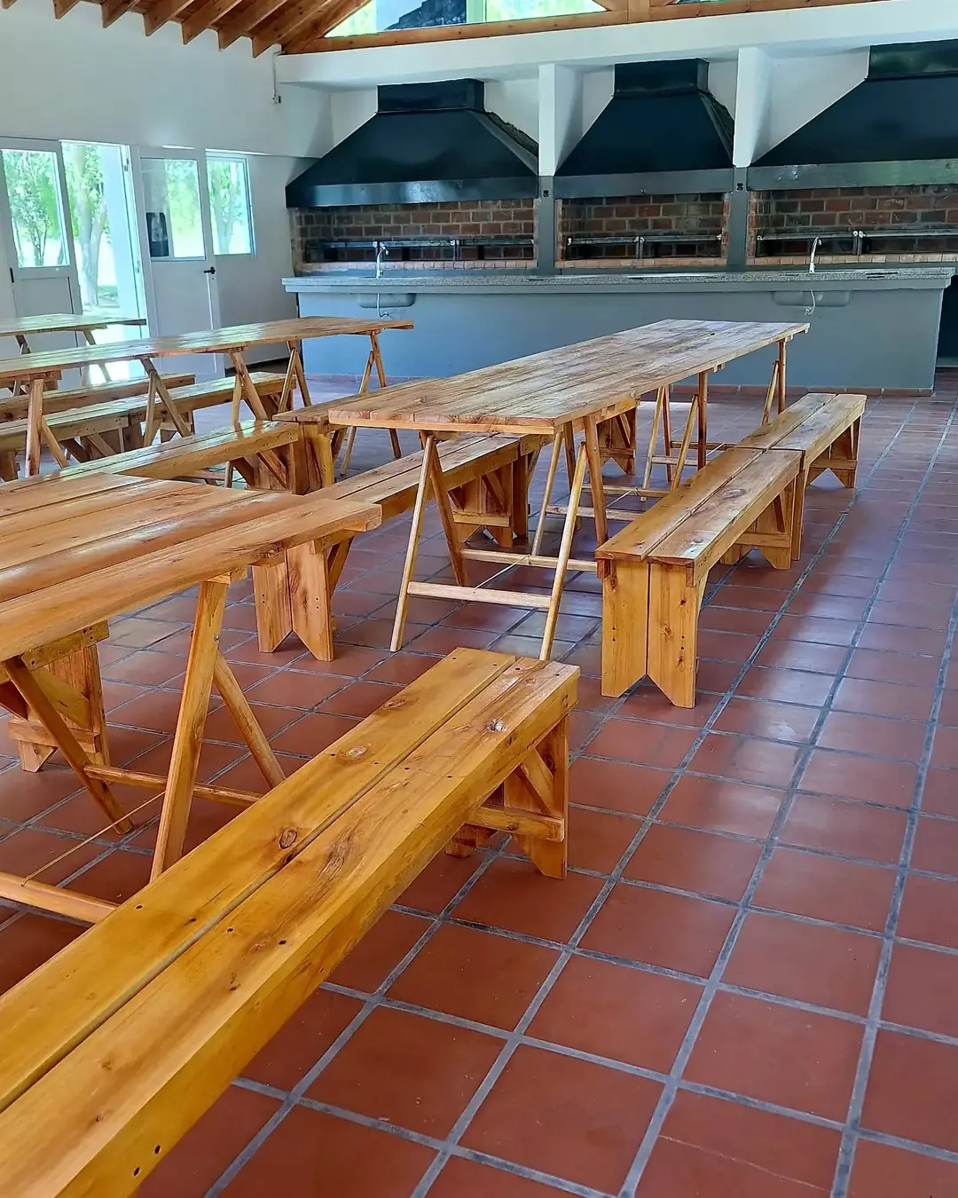 El SUM por dentro, con mesas largas de madera.