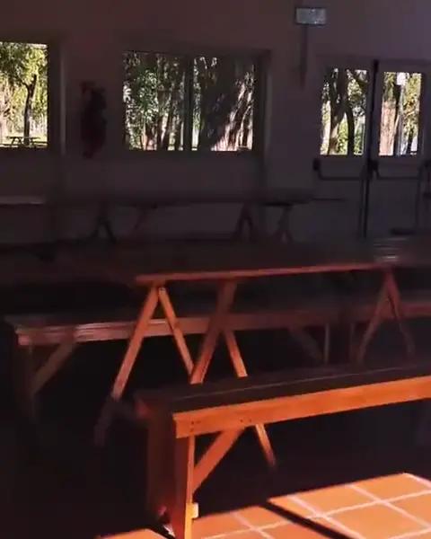 El SUM por dentro: mesas largas de madera con bancos y las parrillas con mesada.
